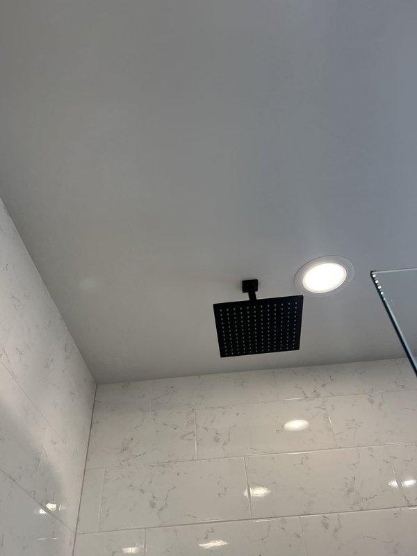 Inspected the master bathroom shower and kitchen faucet location to assess scope for three customer-supplied fixture installations: kitchen faucet replacement, a longer rain shower arm extension, and a handheld showerhead replacement requiring a new slide bar/pole mount. Documented the existing ceiling-mounted matte black rainfall head, wall-mounted handheld bracket, and thermostatic valve configuration on tiled walls, noting all fixtures and surrounding tile are in good condition with no visible damage, and prepared estimates for the work.