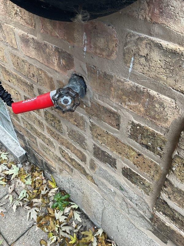 Inspected the cracked porcelain undermount bathroom sink basin and applied repair compound to the crack near the drain to seal the damage, with the chrome faucet and pop-up drain assembly left in place. Also patched the mortar around the exterior hose spigot penetration, restoring a sealed, weather-resistant joint at the brick wall.