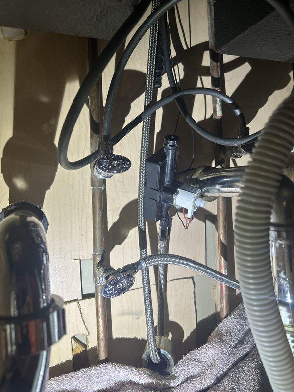 Serviced a Delta touchless (solenoid-operated) pull-down kitchen faucet. With the water supply shut off at the angle stops, the faucet was removed and the under-sink solenoid valve, electronic control module, braided supply lines, and chrome shutoff valves were inspected and prepared for maintenance. Reinstalled the stainless steel faucet with the soap dispenser in place, restored water supply, and verified proper operation and no leaks at connections.
