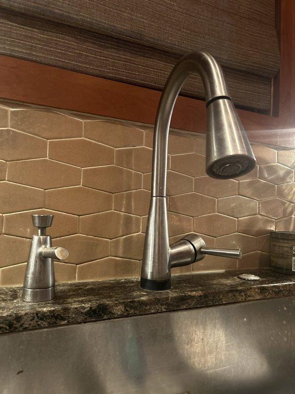 Serviced a Delta touchless (solenoid-operated) pull-down kitchen faucet. With the water supply shut off at the angle stops, the faucet was removed and the under-sink solenoid valve, electronic control module, braided supply lines, and chrome shutoff valves were inspected and prepared for maintenance. Reinstalled the stainless steel faucet with the soap dispenser in place, restored water supply, and verified proper operation and no leaks at connections.
