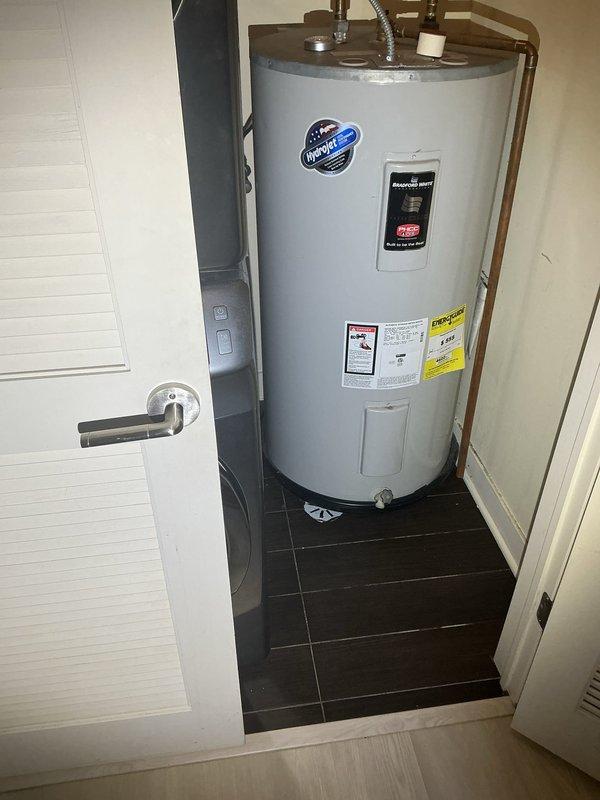Responded to a report of water backing up from the floor drain beneath the water heater during showers and heavy rainfall, indicating a partial obstruction or restriction in the drain line. Inspected the utility closet and surrounding plumbing, confirmed no leaks or visible damage at the water heater or drain pan, and cleared the blockage to restore proper drainage flow.