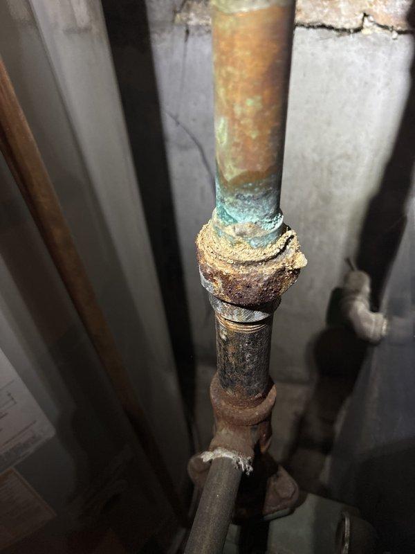 Replaced the corroded copper-to-steel connection on the boiler supply piping, where galvanic corrosion and mineral buildup indicated a prior leak. Removed the deteriorated steel nipple and collar, installed new dielectric-compatible fittings, and sealed all threaded joints. Pressure-tested the system and confirmed it was leak-free, with the boiler, expansion tank, and surrounding piping operating normally.