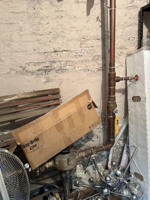 Performed on-site evaluation for a whole-unit water filtration system installation and modification of the kitchen drain piping to allow a code-compliant dishwasher connection. Inspected the main copper water supply, isolation ball valves, and water meter location in the utility area to determine filtration tie-in and bypass placement, and assessed surrounding wall conditions and clearances for equipment mounting. Documented existing conditions with photos and prepared the scope for a written quote covering the filtration installation and kitchen drain reconfiguration.