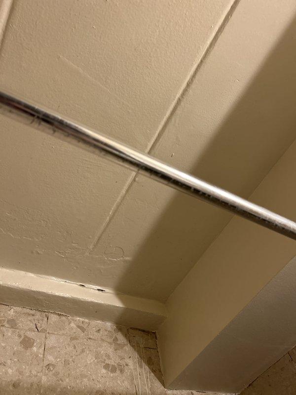 Performed a water leak locate investigation in response to a reported ceiling leak originating from an adjacent bathroom. Inspected the tub/shower alcove and surrounding wall assembly, observing yellow-brown staining and mineral discoloration on the ceramic tile near the tub valve and spout, along the right wall, and at the lower tub edge, indicating moisture intrusion at the faucet penetration and tile/grout joints. Documented findings with photographs, including wear along the tub edge and a possible fastener penetration in the shower door frame as potential water entry points.