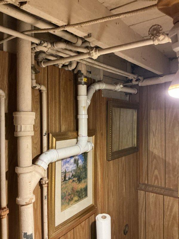 Responded to a kitchen sink drainage complaint and performed a main drain cleanout, accessing the PVC drain assembly and cast-iron stack in the lower-level piping to clear the obstruction and restore proper flow. Inspected the kitchen area, including the sump/condensate pump unit and its corrugated discharge hose and couplings, and verified the drain line was draining freely following the cleanout.