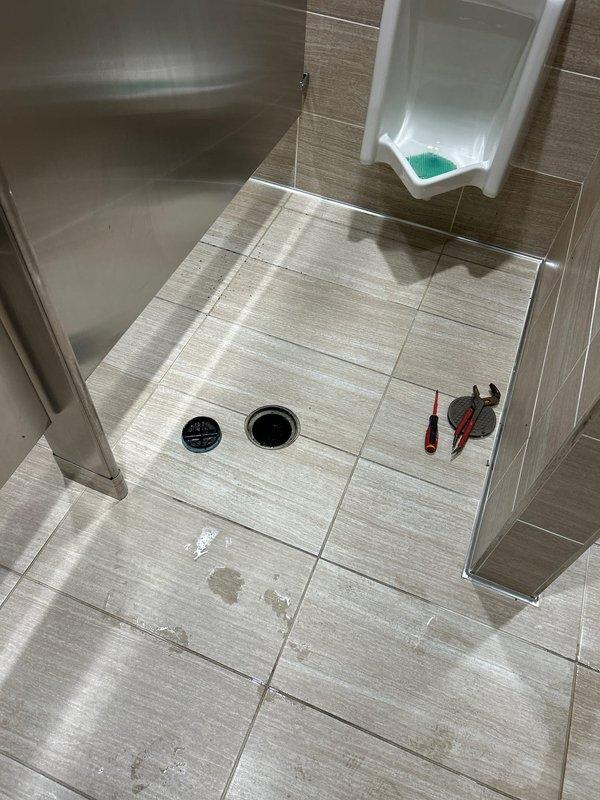 Responded to multiple backed-up drains in a commercial restroom and removed the floor drain grate to access the drain line for clearing. Performed a camera inspection of the drain line to assess pipe condition and identify the source of the stoppage, then restored the line to proper flow. Documented the work area before and after service with photos.