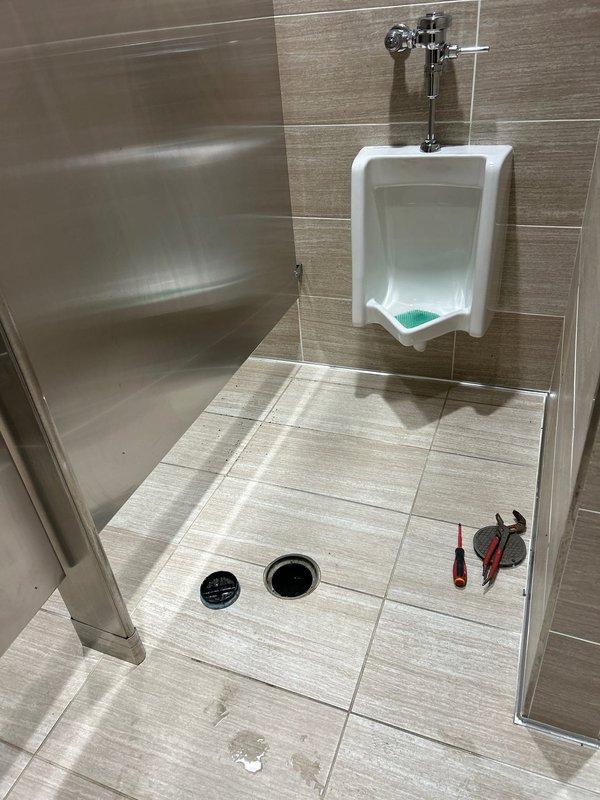 Responded to multiple backed-up drains in a commercial restroom and removed the floor drain grate to access the drain line for clearing. Performed a camera inspection of the drain line to assess pipe condition and identify the source of the stoppage, then restored the line to proper flow. Documented the work area before and after service with photos.