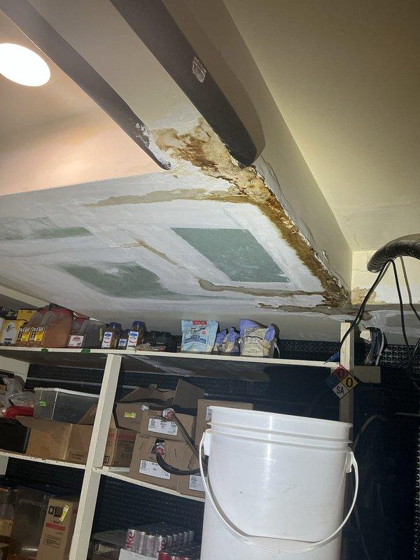 Responded to a sold repair for a water-damaged ceiling in a storage area, inspecting the affected soffit and drywall for signs of an active supply or drain leak. Documented extensive staining, paint failure, and prior patching, and verified the plumbing in the area to identify and address the source of the moisture intrusion. Also assessed the nearby sump and piping in the lower level to confirm proper condition and drainage.