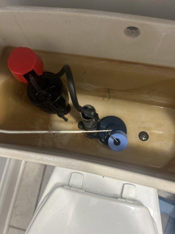 Replaced the fill valve and flapper in a standard gravity-fed toilet using materials stocked on the service vehicle. The tank interior showed heavy mineral and rust staining, and the old components were removed and the new fill valve and flapper installed. Water level was adjusted, and the flush cycle and refill were tested to confirm proper operation with no running water or leaks.