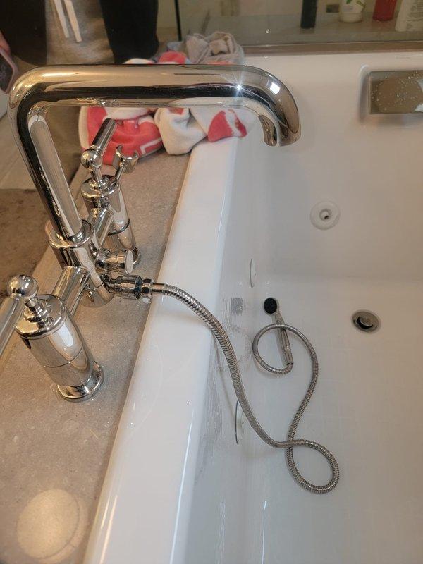 Inspected the reported leaking fixture in the bathroom, which prevented use of the shower. Evaluated the deck-mounted tub faucet and its attached flexible hose and handheld sprayer for leaks and failed connections, and documented the fixture's condition with photos. Provided an estimate for repair or replacement of the faulty components to restore normal operation.