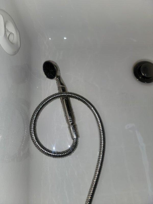 Inspected the reported leaking fixture in the bathroom, which prevented use of the shower. Evaluated the deck-mounted tub faucet and its attached flexible hose and handheld sprayer for leaks and failed connections, and documented the fixture's condition with photos. Provided an estimate for repair or replacement of the faulty components to restore normal operation.