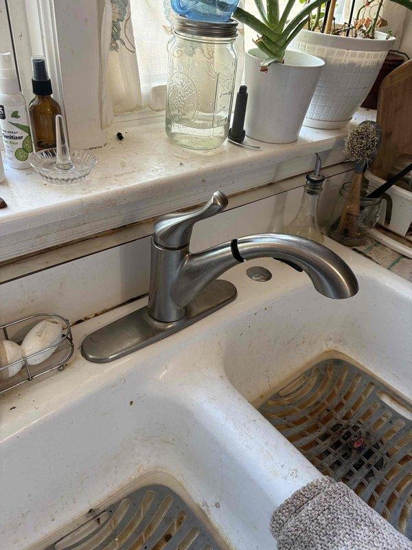Responded to a leaking faucet complaint and inspected the kitchen pull-out faucet and basement bathroom faucet for leak sources. Also assessed the reported toilet leak and checked supply connections and fixtures for water loss. Documented the existing conditions, including staining and wear on the sink and fixtures, with photos.