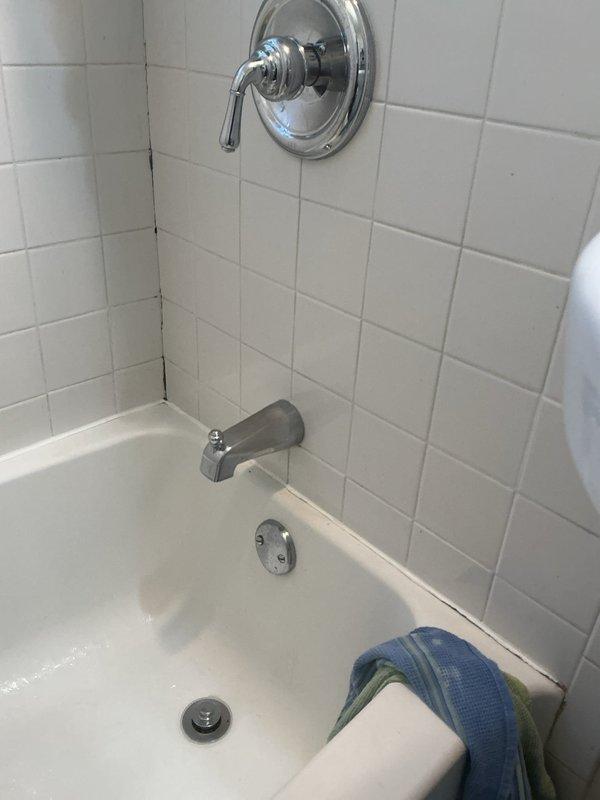 Removed the existing tub diverter spout and installed the customer-supplied diverter spout, then tested for proper operation and diversion to the shower. Applied silicone sealant around the footprint of the new spout to prevent water intrusion at the wall. Installation is covered by a 1-year warranty; the customer-supplied part carries no warranty.