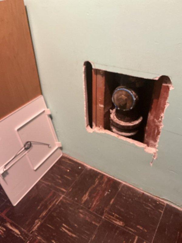 Performed a camera inspection of the drain system, accessing the line through a cut-in access opening in the wall to expose a heavily corroded cast-iron fitting with a hex-head cleanout plug showing significant rust scaling and mineral buildup. Also inspected a deep vertical shaft with layered masonry walls, observing standing water at the base with debris and an object partially visible near the bottom. Findings were documented with photos for further evaluation and recommendations.