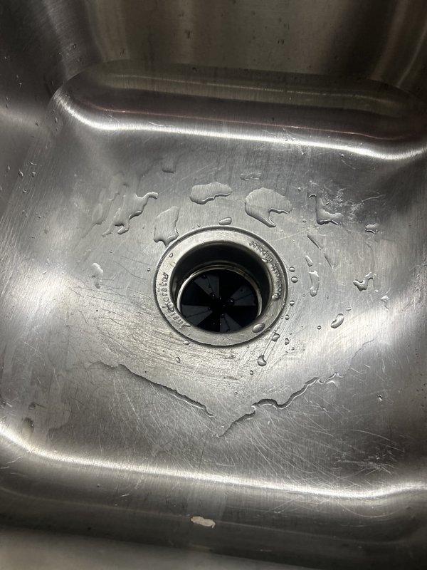 Removed the jammed garbage disposal and installed a new unit, connecting it to the existing sink flange, chrome P-trap, and electrical supply via flexible conduit. Verified secure mounting, leak-free drain connections, and proper operation, with a protective silicone mat placed in the cabinet base.