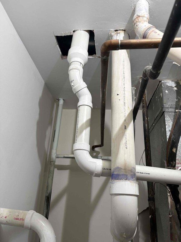 Replaced the aged supply stops with new brass quarter-turn angle valves and braided stainless steel supply lines on the copper supply stubs, restoring reliable fixture shutoff. Reconnected the drain assembly, including the PVC P-trap and corrugated drain hose, and verified all joints for leaks and proper operation. Inspected adjacent copper, PVC, and iron piping in the mechanical space and found no active leaks.