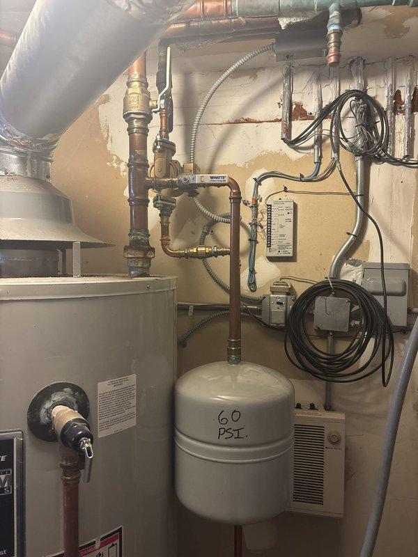 Inspected the water heater installation and found it noncompliant with code, with heavy corrosion at the hot outlet fitting and rust staining on the tank top indicating prior leakage. Corrected the installation by installing a 1-1/2" x 3/4" ProPress tee and a 1-1/2" dielectric union to isolate dissimilar metals, and added a thermal expansion tank set to 60 PSI on the water supply line.