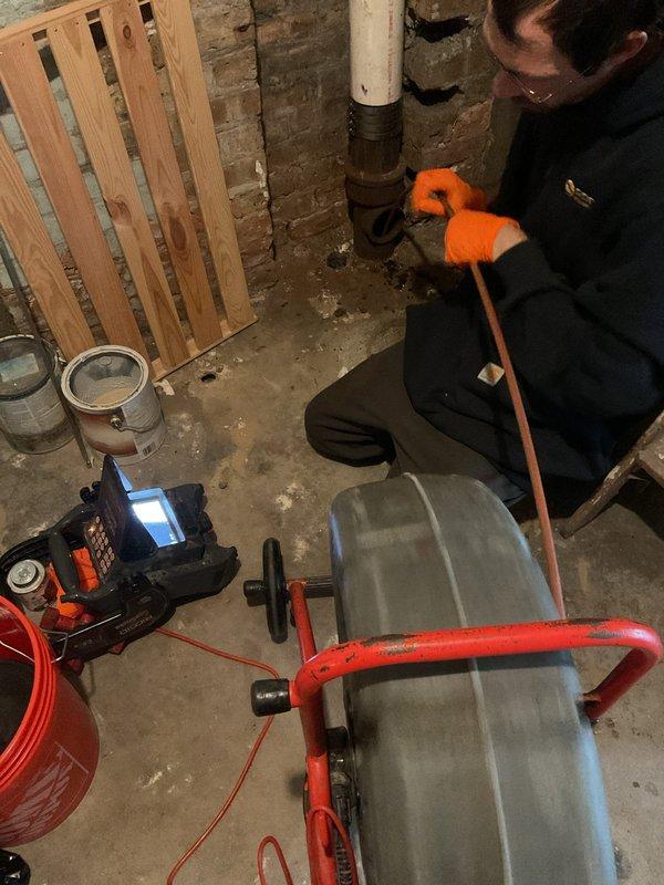Cleared a clogged basement drain using a rod-style drain cable machine fed through the cleanout at the base of the vertical drain stack to break up and remove the blockage. Followed with a camera inspection to verify the line was clear and confirm proper flow through the drain line.