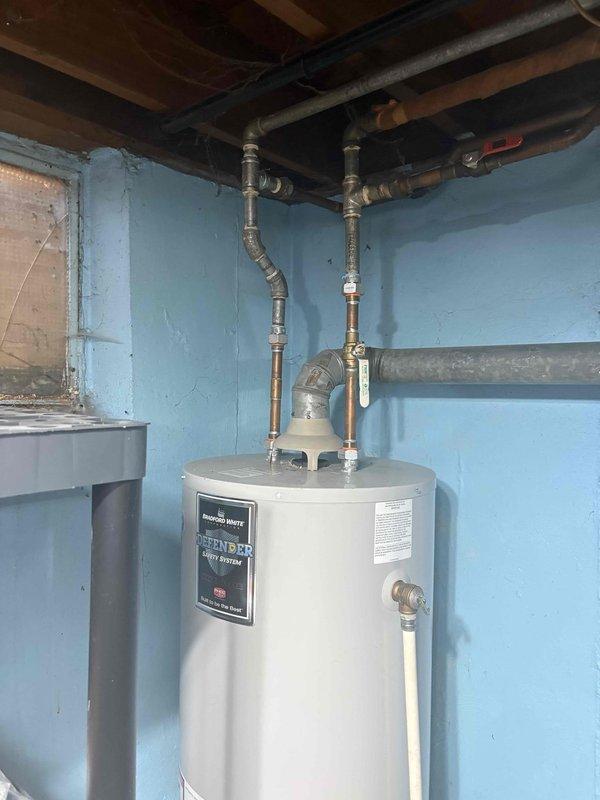 Inspected the Bradford White gas water heater and found sooting and rust staining at the burner chamber, along with a failed thermal switch (flammable vapor/flame rollout protection) mounted on the burner chamber mounting plate. Opened the outer jacket, inspected the burner assembly, wiring leads, and combustion chamber insulation, and verified draft hood and flue venting connection to the exhaust duct. Completed the sold home comfort warranty repair to restore safe, code-compliant operation of the water heater.