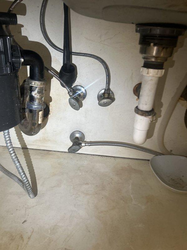 Inspected the hot water supply and under-sink plumbing to diagnose low hot water pressure, documenting the condition of the existing shutoff valves, braided supply lines, and drain assemblies, which showed corrosion, tarnishing, and moisture staining. Evaluated the valves throughout the unit for replacement and prepared a quote for adding a main shutoff valve, with a certificate of insurance to be provided for HOA approval prior to the work.