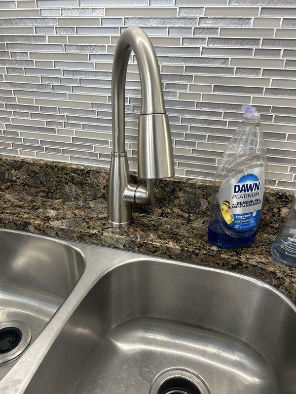 Installed a customer-supplied brushed stainless steel pull-down kitchen faucet on the double-basin sink and replaced the angle stop valves with new chrome shutoff valves and braided stainless steel supply lines. Water was isolated during the work, connections were secured, and the system was restored to service. Inspection of the under-sink area, including the P-trap and garbage disposal connections, found no leaks, corrosion, or damage.