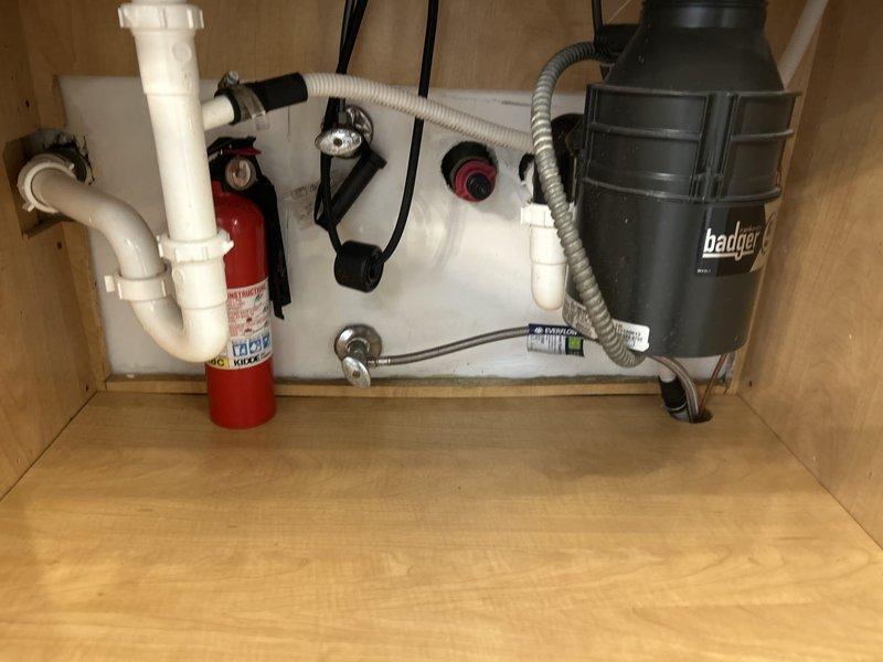 Installed a customer-supplied brushed stainless steel pull-down kitchen faucet on the double-basin sink and replaced the angle stop valves with new chrome shutoff valves and braided stainless steel supply lines. Water was isolated during the work, connections were secured, and the system was restored to service. Inspection of the under-sink area, including the P-trap and garbage disposal connections, found no leaks, corrosion, or damage.