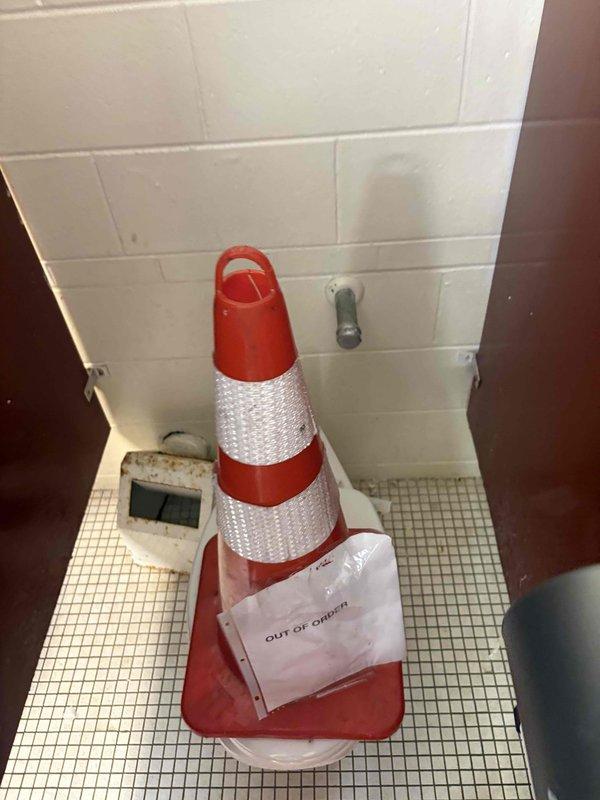 Performed an on-site assessment of the men's and women's restrooms to provide an estimate for fixture repairs and additional water closet installations. Inspected the existing out-of-service toilet and surrounding area, noting corroded wall-mounted fixture, deteriorated mosaic floor tile with exposed substrate, and degraded grout. Measured clearances between the toilet and adjacent wall to verify spacing for proposed fixture placement and documented existing conditions with photographs.