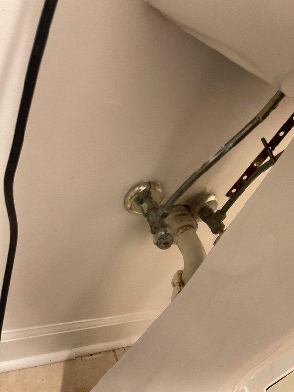 Inspected the toilet for a reported leak at the base and examined the supply connections, angle stop valves, and drain fittings. Observed corrosion and oxidation on the brass connectors and compression nuts at the angle stops, and photographed the area for documentation. Findings are consistent with aging supply components that may warrant further evaluation, and a closer check of the closet flange seal and wax ring is recommended to confirm the source of the leak.
