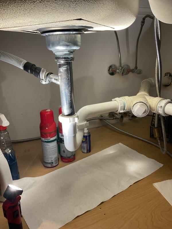 Diagnosed a leak at the dishwasher drain connection on the kitchen sink tailpiece and inspected the P-trap assembly, slip-joint coupling nuts, and corrugated drain hose with clamp. Disassembled and serviced the worn connection, then reassembled the trap and dishwasher drain line to restore a watertight seal. Cleaned up the work area and verified proper drainage and operation of the faucet with no remaining leaks.