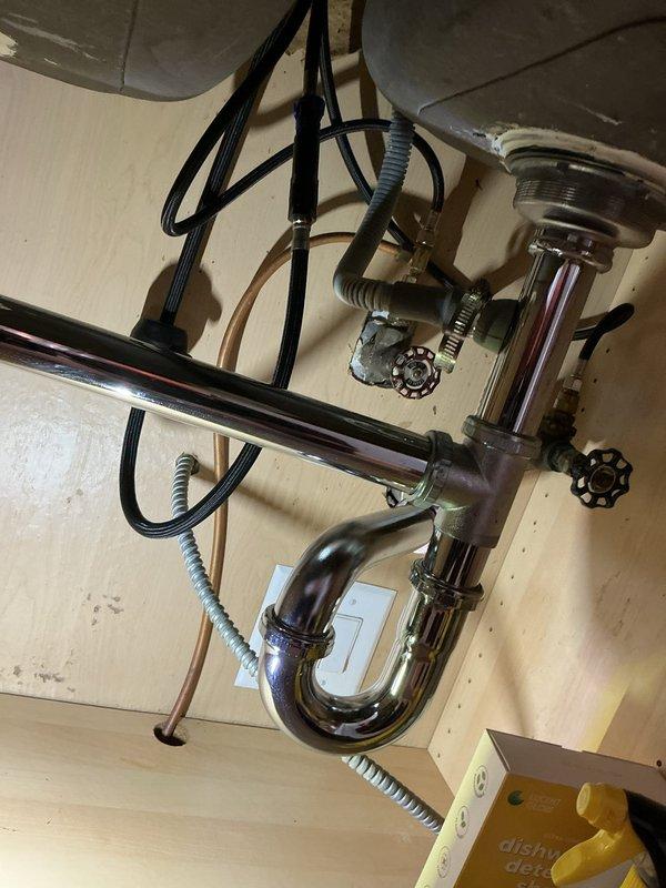 Inspected the kitchen sink supply stops and drain assembly, which showed no leaks, corrosion, or damage, and evaluated the existing GE electric tank-style water heater in the utility closet for removal and tankless replacement. Assessed the bathroom sink supply piping and the feasibility of running a copper supply line to the refrigerator for a water filter, which will require water shut-off during the work.