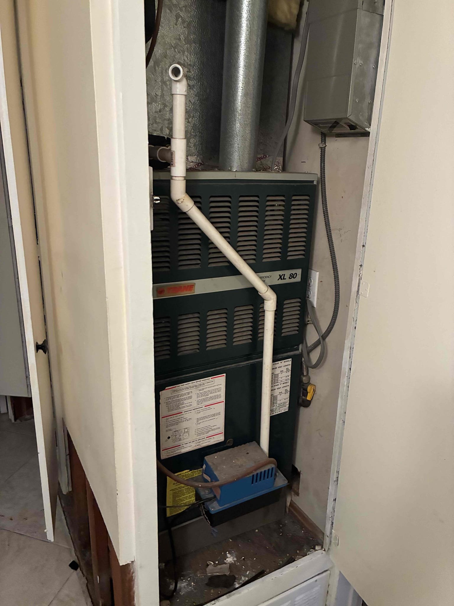 Upon inspection, the 1990 Trane gas furnace exhibited severe issues due to water intrusion from a burst water heater. The electrical components and control board showed clear signs of water damage. The blower fan operated continuously, while the inducer motor failed to energize during a heat call. Motor bearings sounded rough and noisy, indicating further damage. Given the furnace's age and the extent of water damage, full system replacement is recommended for reliability. If a short-term repair is preferred, the inducer motor, blower motor, and control board would need replacement. However, this repair is not guaranteed due to the system's age and potential unseen internal corrosion.