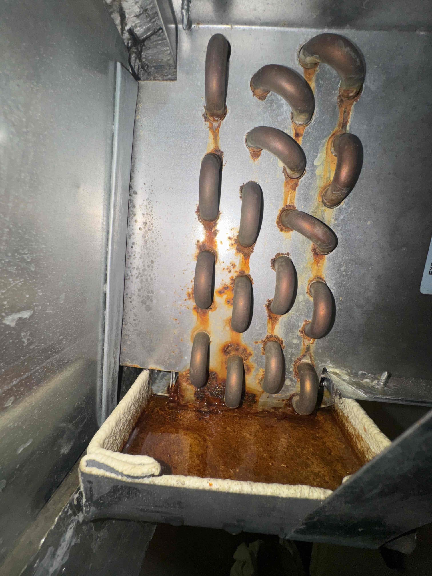 I inspected the fan coil and identified a leak originating from the condensate water drain pan. Upon further examination, I discovered that the primary copper condensate drain line was clogged, hindering proper drainage. I traced the line's exit path and found it led beneath the bathroom sink. To resolve the issue, I recommended clearing the line using a nitrogen blowout method. Additionally, I suggested installing pan tabs to prevent future buildup and ensure efficient drainage. This approach will help maintain the system's performance and prevent similar issues in the future.