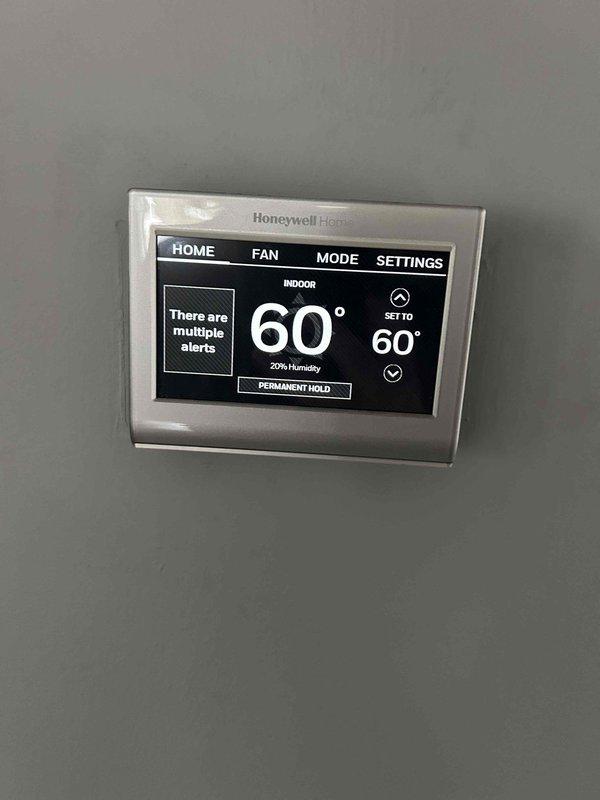 Completed care plan tune-up service on heat pump/air handler system located in garage. Performed visual inspection of capacitor and electrical connections, noting proper wiring configuration. Checked Honeywell thermostat operation, which displayed 60°F with 20% humidity and had active system alerts. Replaced existing filter with AprilAire #310 filter as part of maintenance protocol.