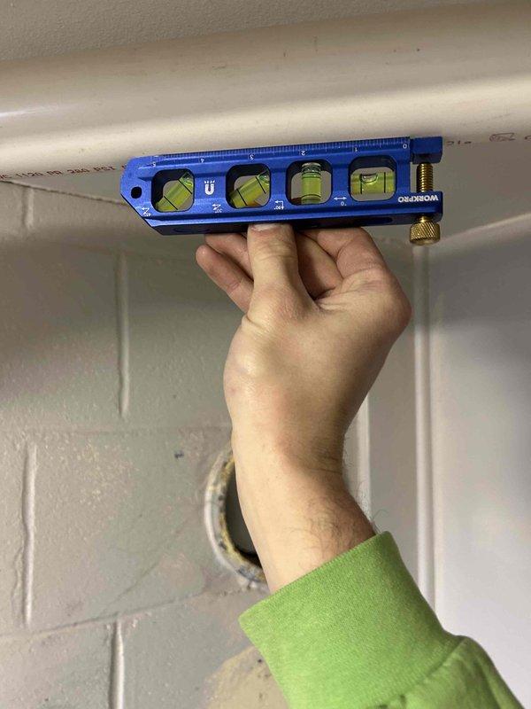 Responded to warranty call regarding excess water discharge from exhaust system. Inspected installation and used torpedo level to verify proper condensate drainage pipe slope on the PVC vent system. Adjusted pipe mounting brackets to ensure correct pitch for proper condensate flow, resolving the drainage issue.