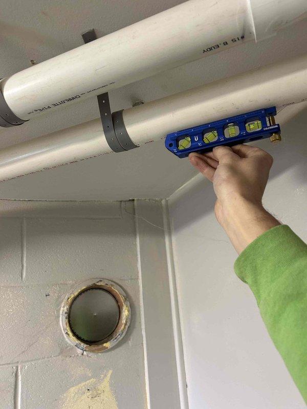 Responded to warranty call regarding excess water discharge from exhaust system. Inspected installation and used torpedo level to verify proper condensate drainage pipe slope on the PVC vent system. Adjusted pipe mounting brackets to ensure correct pitch for proper condensate flow, resolving the drainage issue.