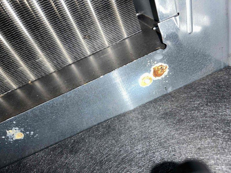 Responded to customer-reported intermittent water leak beneath HVAC unit. Inspection revealed corrosion spots on the heat exchanger panel, indicating moisture exposure over time. Located source of leak at the plumbing connection near the blue valve assembly, repaired affected components, and confirmed system operation before completing service.