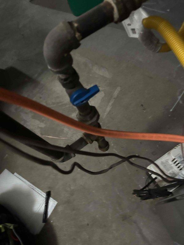 Responded to customer-reported intermittent water leak beneath HVAC unit. Inspection revealed corrosion spots on the heat exchanger panel, indicating moisture exposure over time. Located source of leak at the plumbing connection near the blue valve assembly, repaired affected components, and confirmed system operation before completing service.