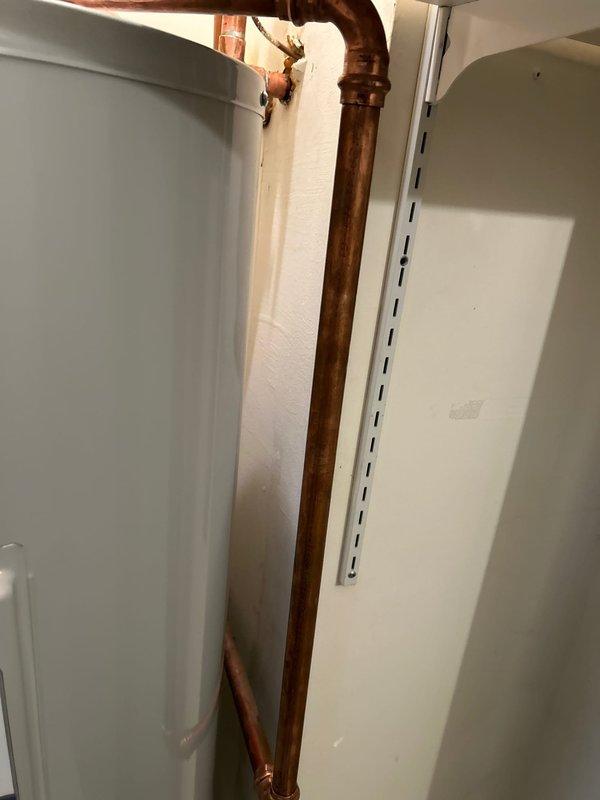 Installed new tanked water heater with proper elevation to accommodate drain pan and discharge system. Modified drywall behind washing machine to establish drainage connection. Connected copper supply lines with appropriate fittings and installed gas valve. Confirmed system functionality before completion.