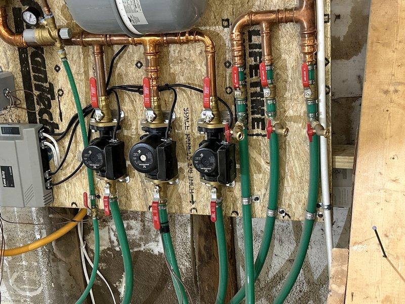 Successfully reconnected green PEX piping from the newly installed air handler to the existing hydronic system with three circulation pumps. Restored water flow to the system and verified proper operation of all components.