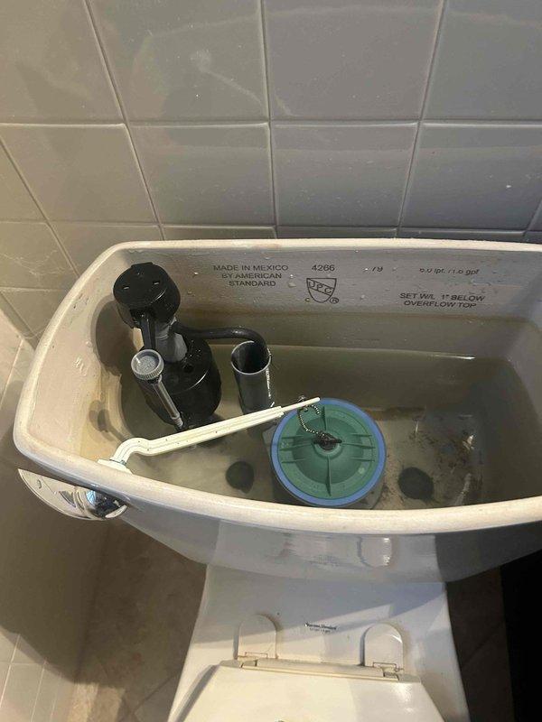 Identified and replaced faulty toilet fill valve that was continuously allowing water to leak into the flush valve despite the float cup reaching its stopping position. Removed old assembly showing mineral buildup, installed new fill valve mechanism to restore proper water shutoff function and eliminate continuous running.
