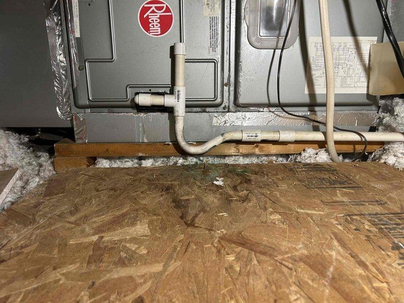 Responded to non-urgent service request regarding gurgling sounds in condensate drain line. Inspected Rheem HVAC system located in attic space, examining the condensate drain assembly and surrounding structural components. Cleared blockage in condensate drain line, removing accumulated debris to restore proper drainage function and prevent potential water damage to ceiling below.