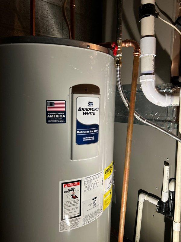 Successfully replaced a 50-gallon Bradford White electric water heater in utility area. Installed new copper supply lines with appropriate valves and fittings. Connected PVC discharge piping according to code requirements.