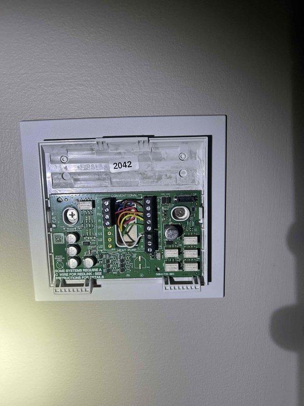 Responded to call back regarding heating and cooling system's inability to maintain target temperatures. Upon investigation, inspected Honeywell thermostat displaying proper readings (65° indoor/25° outdoor) and operating in Heat mode. Removed thermostat cover to examine wiring connections at terminal block, verifying proper wire placement and secure connections for red, yellow, green, and white wires. All components tested functioning correctly after service.