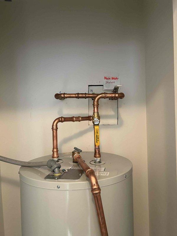 Replaced cracked plastic drain pan with new metal drain pan beneath recently installed water heater per homeowner's request. Verified proper installation with no leaks at connections. All water heater systems functioning correctly after service.
