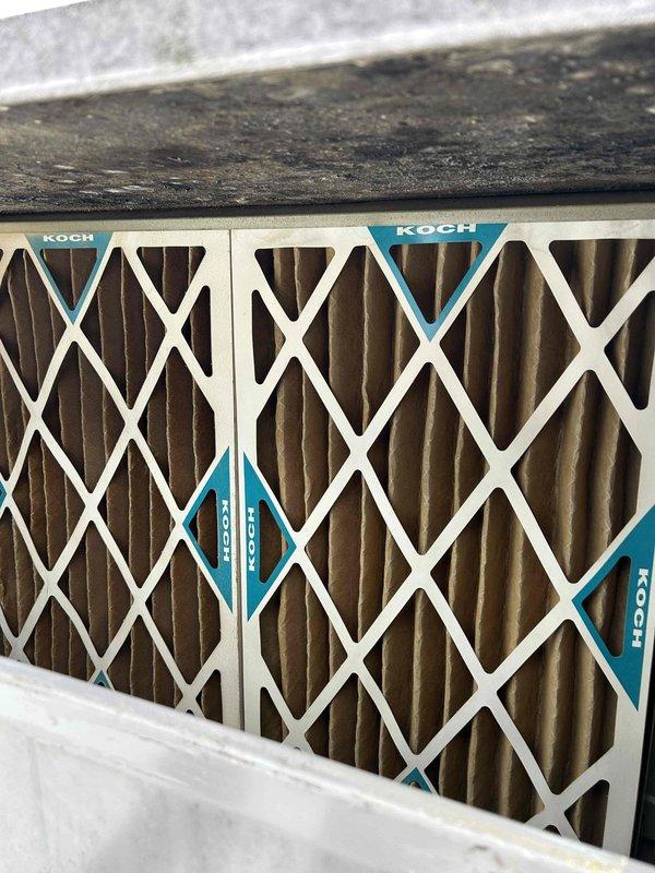 Performed commercial HVAC tune-up at bakery location using ladder to access rooftop unit (RTU). Inspected and checked Koch air filters, which were installed correctly but system showed signs of extended use with some accumulation on housing surfaces. Examined exposed internal components including wiring, coils and mechanical parts, verifying proper operation of the system.