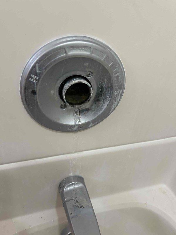 Inspected leaking shower/tub fixture with chrome valve and handle assembly. Identified mineral buildup and wear on the escutcheon plate contributing to the leak. Repaired valve mechanism while maintaining access behind the wall-mounted components. Customer's shower remains functional following service completion.