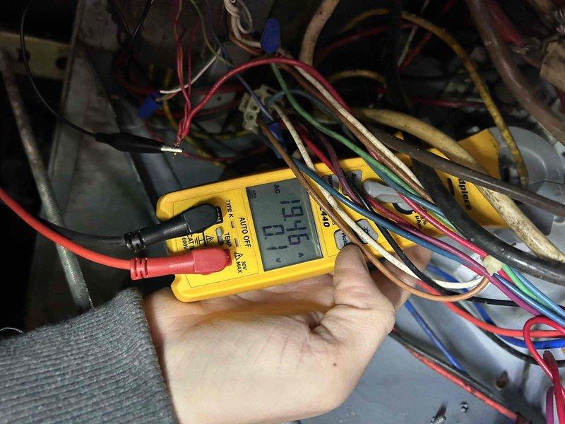 Performed tune-up service on 10+ year old heat pump system with air handler located in crawlspace. Conducted electrical diagnostic testing on the outdoor condenser unit, measuring voltage (196.0V) with digital multimeter to verify proper electrical supply. Unable to inspect air filter as customer and son could not locate it; recommended standard replacement filters and documented filter size information for future reference.