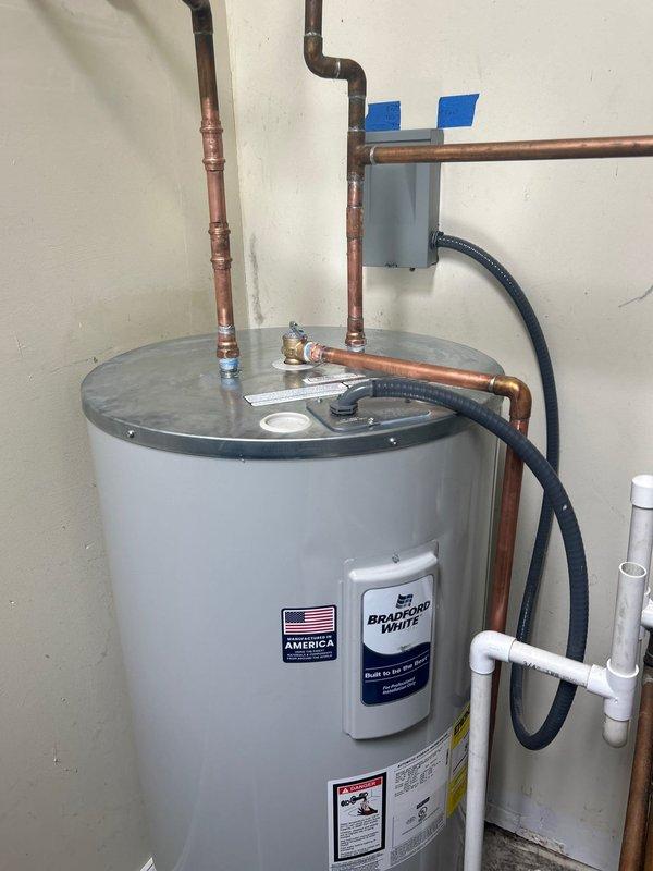 Successfully installed a 50-gallon Bradford White electric water heater, replacing the previous unit. Properly drained the old heater before disposal. Connected the new unit to the existing geothermal system via a tee fitting at the bottom of the tank. Completed all necessary copper pipe connections, verified proper functionality, and confirmed no leaks present upon completion. Installation includes 6-year tank/parts warranty and 1-year labor warranty.