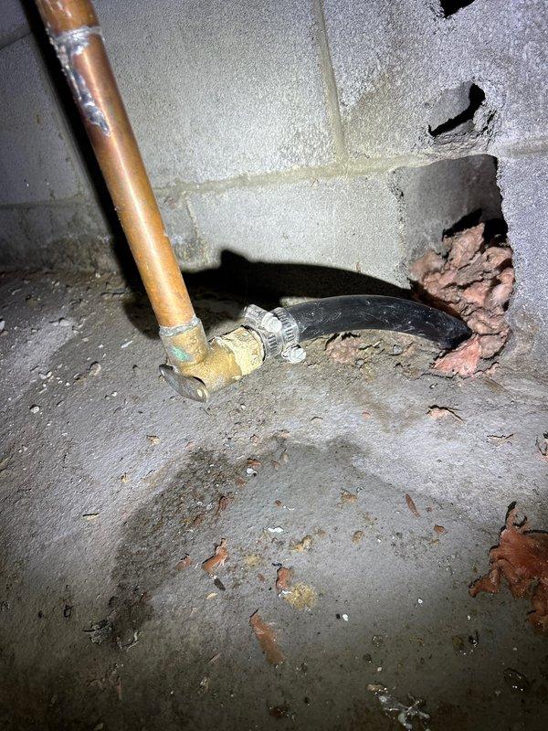 Conducted PSA plumbing inspection of water heater system and associated plumbing. Examined water heater installation with multiple supply/return lines, including red flexible pipes and metallic braided hoses with brass fittings. Identified deterioration around pipe penetration in concrete wall where copper supply pipe enters, showing signs of crumbling concrete that may require future attention.