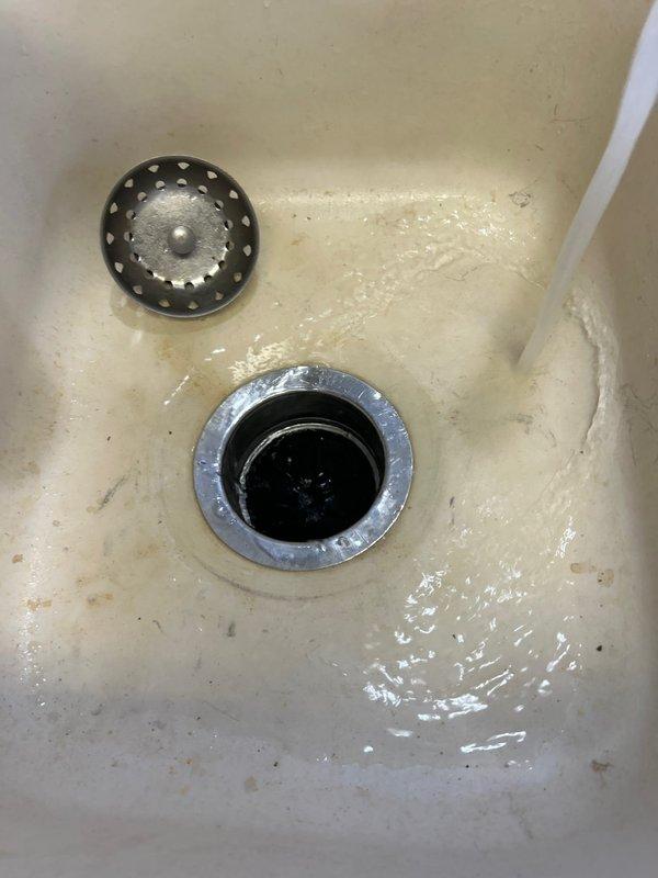 Responded to service call for slow-draining 5-6 year old garbage disposal. Diagnostics revealed clog in the drain line causing water to back up into the sink basin. Successfully removed blockage and verified proper drainage by testing water flow. All components now functioning correctly with no leaks observed.